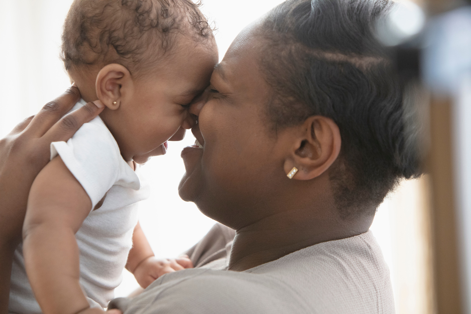 Smiling Black mother kissing baby daughter